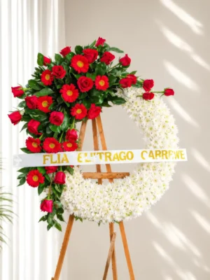 Corona Fúnebre Eternidad de crisantemos blancos con cascada de rosas y gerberas rojas, sobre atril de madera.
