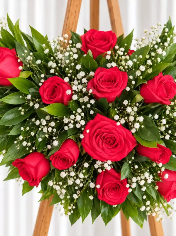 Detalle de la Corona Fúnebre Lazos de Amor: rosas rojas con gypsophila y follaje verde.