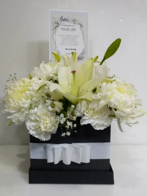 Ramo fúnebre en caja negra con crisantemos, lirios y claveles blancos y tarjeta de condolencias