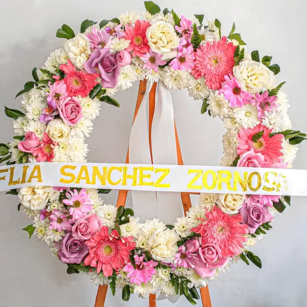 Corona de Velorio con rosas, margaritas y pompones con tonos rosados y blancos. Domicilio a sepelios en Bogotá.