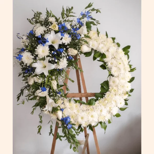 Elegante Corona Fúnebre de hombre con rosas, lirios y pompones blancos simbolizando el luto. Envíos a velorios de Bogotá.