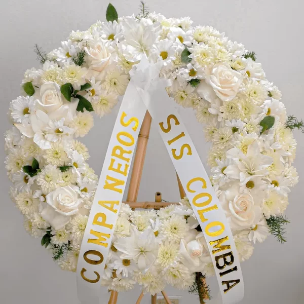 Elegante Corona de flores llena de rosas, margaritas y lirios blancos que transmiten paz y consuelo en los funerales de difuntos en Bogotá.