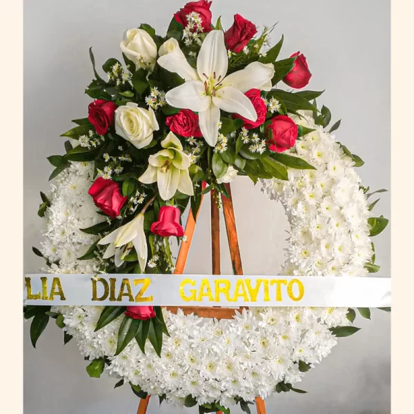 Elegante Corona Fúnebre con lirios blancos, rosas y pompones para velaciones en Sepelios de Bogotá.