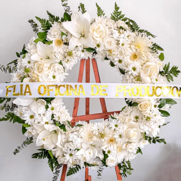 Corona de flores Exequiales como rosas, margaritas, gerberas y pompones blancos. Su diseño simple es símbolo de condolencias.