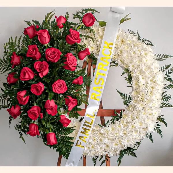 Corona de condolencias con flores de luto como las rosas rojas y los pompones blancos para exequias en Bogotá.