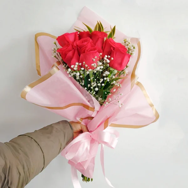 Bouquet de Flores Centella con rosas rojas y gypsophila, en papel rosado con borde dorado y moño rosado.