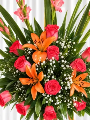 Detalle de la Corona Fúnebre Amor: rosas rojas, lirios naranjas y gypsophila, con gladiolos rosados y hojas largas arriba.
