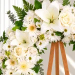 Detalle de la Corona Fúnebre Esmeralda: lirios blancos, rosas crema, gerberas y margaritas blancas con helecho y eucalipto.