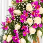 Detalle de la Corona Fúnebre Hechizo de Paz: rosas blancas, orquídeas fucsia y gypsophila entre helecho.