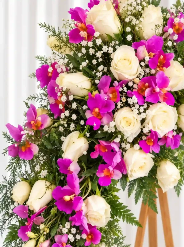 Detalle de la Corona Fúnebre Hechizo de Paz: rosas blancas, orquídeas fucsia y gypsophila entre helecho.