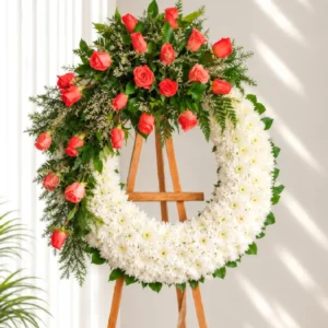 Corona Fúnebre Memoria circular de crisantemos blancos con media corona de rosas coral, caspia y follaje, sobre atril de madera.