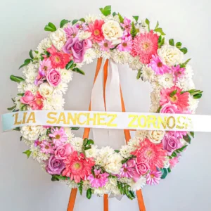 Corona de flores rosadas fucsias blancas gerberas rosas dalias claveles atril