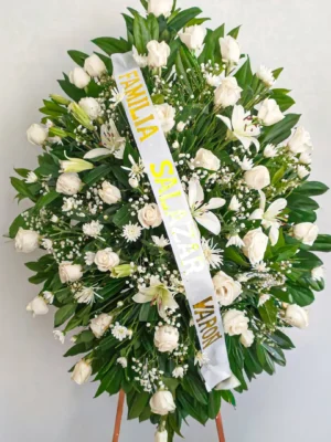 Pedestal fúnebre ovalado con rosas y lirios blancos y flor de relleno sobre atril de madera