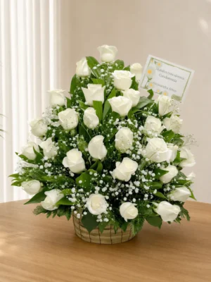 Ramo fúnebre en canasta de mimbre con abundantes rosas blancas y gypsophila, con tarjeta de condolencias
