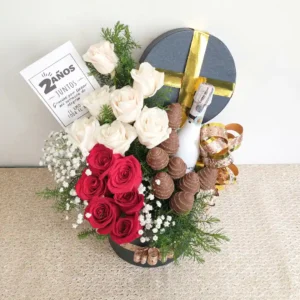 Ramo con rosas rojas y blancas, gypsophila, fresas con chocolate y vino en caja redonda negra decorada con detalles dorados.