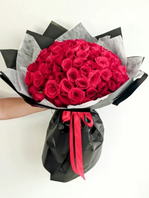 Ramo Buchón con 100 rosas rojas premium, envuelto en papel negro mate con lazo rojo, ideal para ocasiones románticas especiales.