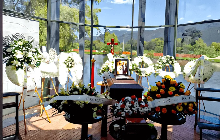 Sala de velación de la funeraria de Jardines del recuerdo en Chía o Bogotá, lleno de arreglos y coronas de flores expresando luto y condolencias.