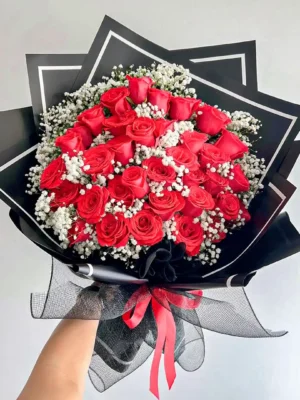 Ramo Buchón de rosas rojas con gypsophila blanca, diseño elegante con papel negro y lazo rojo vibrante.