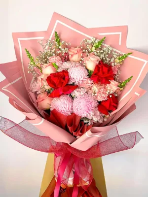 Bouquet de Flores Lumiere con rosas rojas y rosadas, crisantemos rosados y gypsophila, en papel rosado.