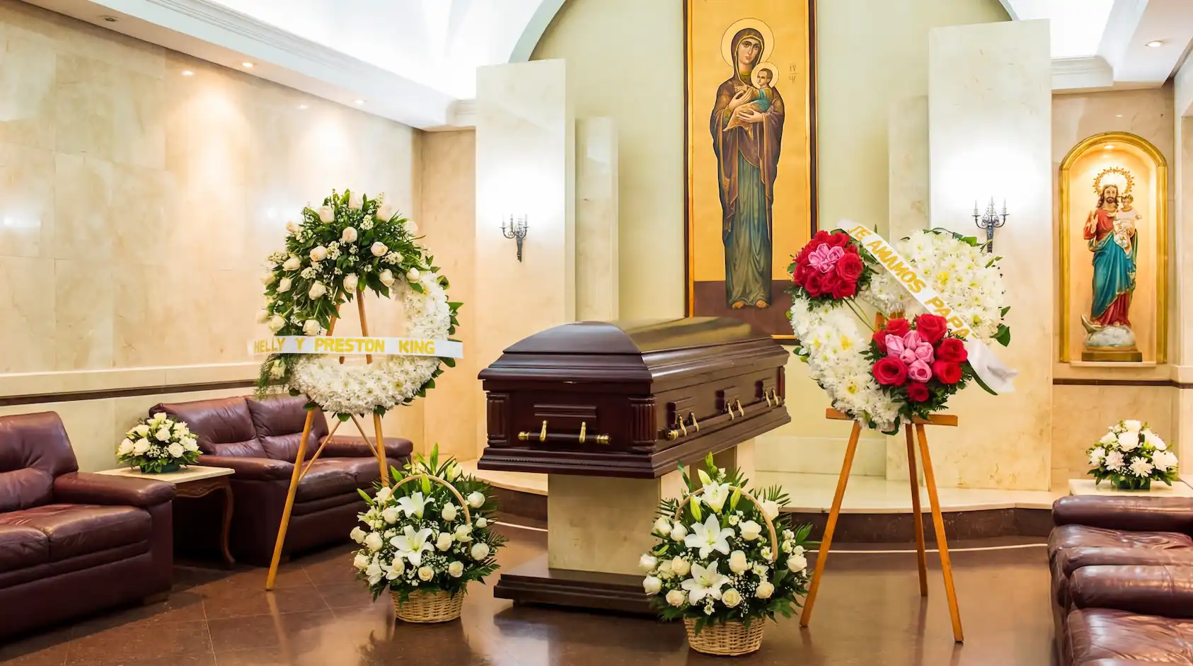 Arreglos fúnebres con coronas de rosas y canastas de lirios blancos en capilla de la Funeraria La Candelaria sede del Chicó