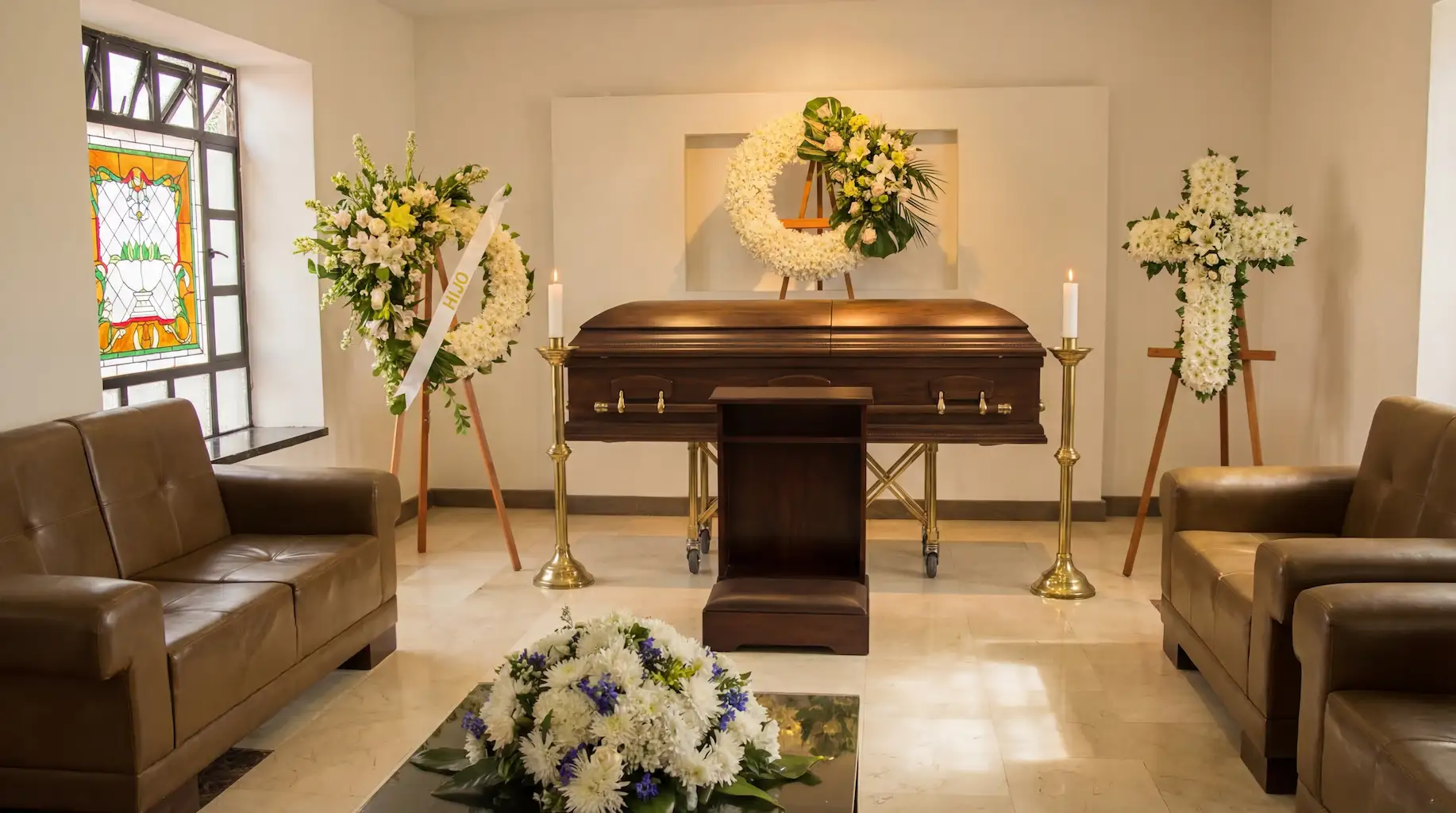 Coronas para funeral con flores blancas y cruz floral acompañando velación en sala de Funeraria Los Olivos sede Restrepo